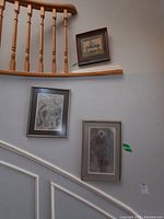 Three framed wall art prints hung on a staircase wall, showing varying sizes and styles.