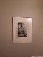 Photo of the first framed black and white print featuring a flower arrangement in a pot beside a rustic window, framed with a mat board and thin metallic frame.