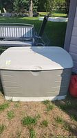 Front of beige Rubbermaid garden storage bin outdoors on grass
