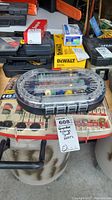 Photo showing two boxes of rotary tool accessories placed among other tool cases, the front box is labeled and holds a variety of bits and attachments visible through a clear plastic lid.