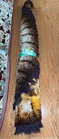 Rolled shag area rug showing the thick plush pile and fringe, highlighting multi-color pattern including brown, yellow, white, and orange.