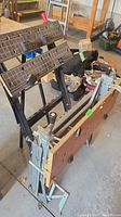 Two Workmate portable workbenches leaned side by side showing wooden tops with measurement markings and foldable metal legs.