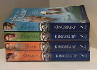 Four Karen Kingsbury paperback books from the FirstBorn Series stacked horizontally, showing spine titles and author name.
