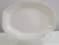 Full view of the octagonal white platter with inner ribbing on a clear stand.