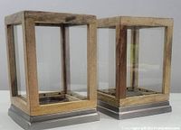 Pair of new lantern style pillar candle holders with wood frames, glass panels, and metal bases shown from front and side angles.