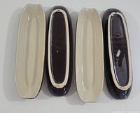 Four vintage ceramic corn dishes displayed top-side and bottom-side. Cream colored interiors and dark brown exteriors visible. Some glaze wear noted on bottoms.