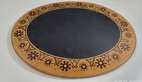 Top-down view of the round vintage charcuterie board showing the entire surface, centered black oval and decorative outer border.
