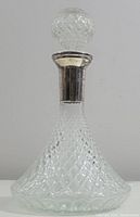 Full decanter showing diamond cut glass body, round stopper and silver-plated collar.