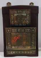 Front view of vintage wood wall-mounted mail organizer with ornate brass panels labeled 'Letters' and 'Papers'. Shows wood frame and brass detailing.