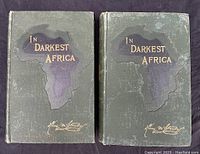 Front covers of volume I and II of 'In Darkest Africa' showing the green cloth with gold embossed titles and African continent outline.