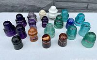 Front-angled group shot of all 17 antique glass insulators showing colors and profiles