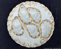 Overhead view of plate showing five oyster wells and gold gilding on white porcelain