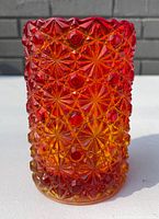 Side view of Amberina glass spooner showing vivid red and amber color gradient and Buttons and Bows textured pattern