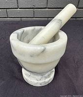 Stoneware mortar and pestle set showing the pestle balanced inside the mortar from a side angle.