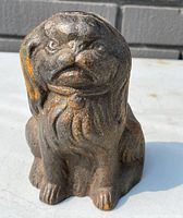 Front and angled view of the figural cast iron pug dog door stop showing detailed face and textured fur with some rust spots.