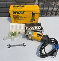 Photo showing DeWalt DW670 laminate trimmer, original yellow box, instruction manual, wrench, power cord neatly coiled, and small parts in plastic containers on a white surface outdoors.