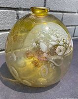 Front view of large yellow glass paperweight showing controlled internal bubble formations and a small top opening.