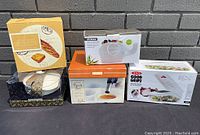 All items in lot shown together revealing packaging and size, includes cheese plates, elephant serving bowl, torch set, vegetable chopper.