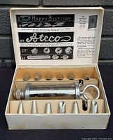 Top view of iced barrel set with all nozzles and spherical tips arranged in original box with printed instructions on inside lid.