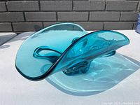 Side view showing the fluid curved shape and translucent blue color of the blown glass bowl.