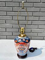 Full view of Japanese Imari porcelain lamp showing size, shape, and design on base, also showing lamp harp and cord.