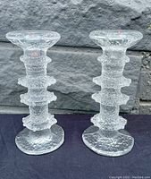 Front view of two clear glass candlesticks with textured ice glass design and irregular sculpted ridges.