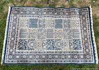 Full view of vintage navy Nain area rug laid on grass, showing patchwork design and border.