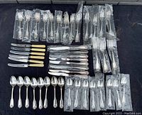 Full view of the flatware set including forks, knives, and spoons mostly packed in bags.