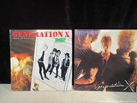 Photo showing two vintage Generation X punk rock vinyl record albums. One is 'Valley of the Dolls' with a black and white cover showing four band members. The other is a color photo of the band with five members and the title 'Generation X'. Both show normal age wear.