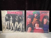 Two vinyl records by Ramones, 'Rocket to Russia' and 'End of the Century', with visible covers and protective plastic sleeves.