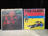 Photo shows two vintage vinyl record albums by The Clash side-by-side on a surface with natural light.