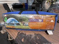 Tent bag showing Ozark Trail branding and product image of a blue and gray dome tent set up outdoors with campers.