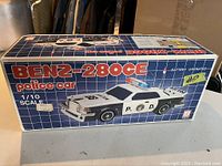 Box showing Benz 280CE police car model, scale 1/10, battery operated, new in box.