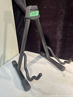 Front angled view of folding guitar stand showing rubberized hooks and feet
