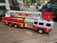 Side view of the Tonka fire rescue truck toy sitting on a table outdoors, showing ladder and side decals.