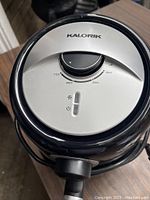 Top view of Kalorik air fryer showing temperature control dial and power indicator light on silver panel with black trim.