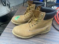 Side view of the pair of Timberland leather work boots showing tan nubuck leather, padded black collar, metal eyelets, and Timberland logo on heel.