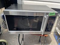 Full front view of stainless steel Hamilton Beach microwave showing stainless steel finish, black glass door, and handle