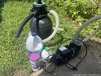 Aqua Pro sand filter sphere tank with attached hoses and pool pump on outdoor concrete and grass background