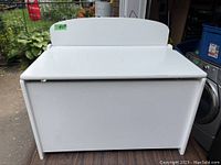 Front view of the white wooden toy box with closed lid and rounded back panel.