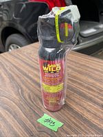 Single Sabre Wild Max Bear Attack Deterrent spray in original plastic wrap on brown wood surface showing front label with brand and black bear graphic.