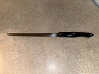 Full length side profile of the bread cutting utensil showing blade and handle