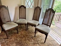 Four wooden dining side chairs with tall cane backs and sage green upholstered seats arranged on carpet
