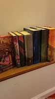 Side view of all seven Harry Potter hardcover books showing colorful dust jackets and spine titles.