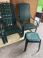 Two green cantilever patio chairs with woven plastic straps and matching small green plastic Parsons table in front