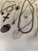 Photo showing multiple sterling silver jewelry items including necklaces with pendants, rings, and an oval pin.