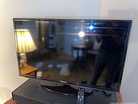 Samsung 32 inch Smart TV front view with remote on base.