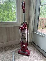Full upright view of the Shark Navigator Swivel vacuum showing red color, ergonomic handle, clear dirt canister with dust inside.
