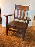 Left angled view of the vintage oak chair showing the armrest and side structure.