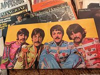 Top view of The Beatles Sgt. Pepper's Lonely Hearts Club Band gatefold album open showing the four band members in colorful military-style uniforms.